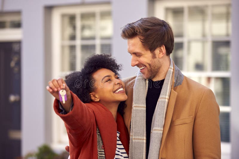 smiling-multi-cultural-couple-outdoors-moving-day-holding-keys-to-new-home-fall-winter-242175764.jpg